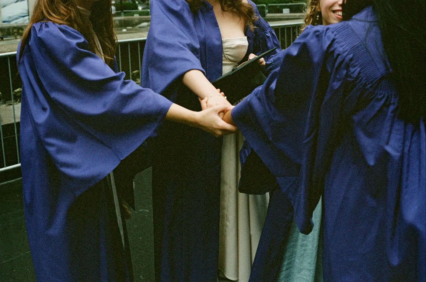 McKenzie Waddell and friends holding hands in NYU graduation gowns